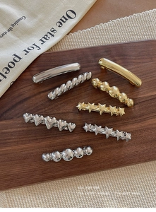 Detailed close-up of mixed metal hair clips including gold star and heart designs