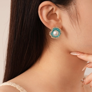 Gros plan de boucles d'oreilles perles avec émail bleu plissé et détails en cristaux