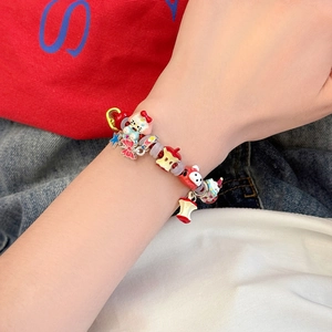 Détail du bracelet en corde tressée avec breloques chat, pomme et nœud en émail