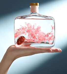 Detail view of decorative glass bottle with pink dried flowers and pine cones for room fragrance