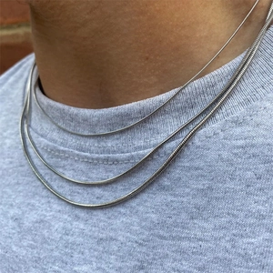 Three-piece set of silver stainless steel snake chains worn by a model in layered style
