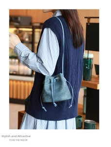 Detail of grey-blue drawstring bucket bag showing water-ripple texture and leather strap