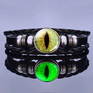 Detailed view of dragon eye leather bracelet with yellow glass gem on reflective surface