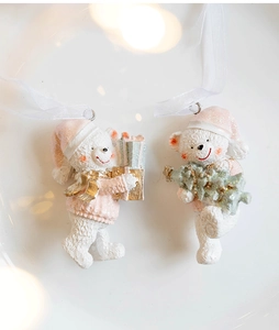 Close-up of white resin Christmas bear pendants with pink glitter hats and gold gift box