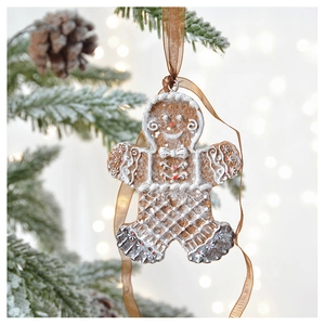 Detail of gingerbread man Christmas ornament with white frosting hanging on pine tree