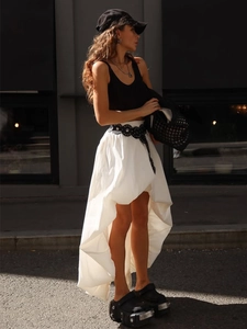 Détail d'une jupe en coton asymétrique blanche avec ourlet irrégulier et ceinture