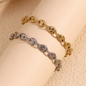 Close-up of gold and silver coffee bean link chains on wrist with metallic luster