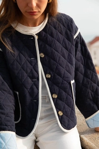 Close-up of diamond-quilted jacket with contrast white piping and striped sleeve lining
