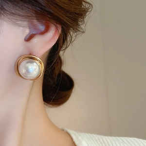 Detailed close-up of a French vintage round pearl earring with a gold spiral metal frame
