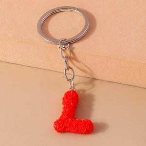 Macro detail of red 3D rose-textured letter L keychain with silver metal ring