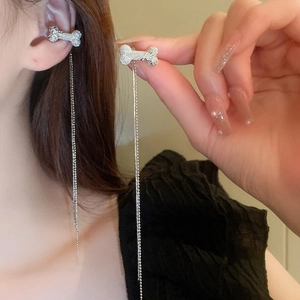 Détail de manchette d'oreille argentée en forme d'os avec longues chaînes à franges