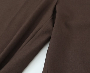 Macro shot of dark brown twill fabric texture and fine stitching detail on the suit set