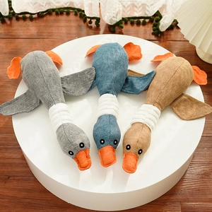 Detailed texture of duck-shaped plush pet toys in grey, blue, and brown linen fabric