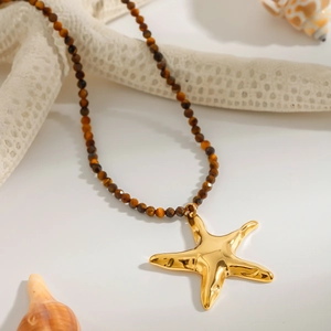 Detail of gold starfish pendant on brown beaded necklace with beach decor elements