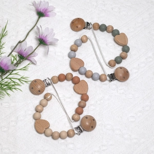 Detail of wooden baby pacifier clip with silicone beads and heart-shaped beech wood decor