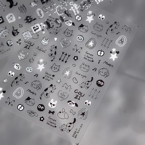 Close-up of embossed silver and black nail art stickers with cats and stars