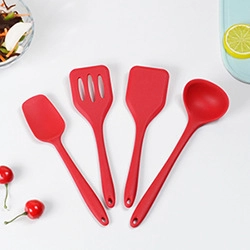 Set dettagliato di spatole, spatola forata e cucchiaio in silicone rosso su sfondo bianco