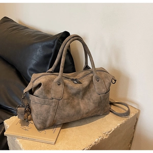 Macro shot of brown retro Boston bag showing brushed leather texture and metal zipper details
