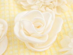 Dettaglio macro di applicazioni floreali in raso 3D su gonna in tweed con petali