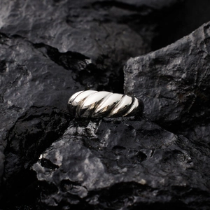 Macro shot of silver croissant ring with polished spiral texture on black raw stone
