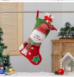Detail of red and green knitted Christmas stocking with snowman design in festive setting