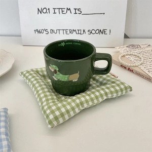 Gros plan sur un dessous de verre à carreaux verts avec mug de dessin animé