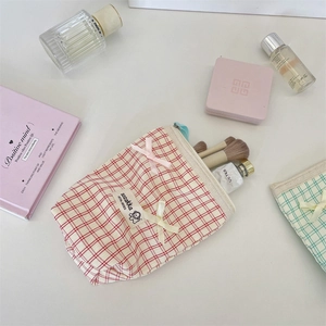 Close-up of plaid fabric toiletry bags with ribbon bows and interior cosmetics storage