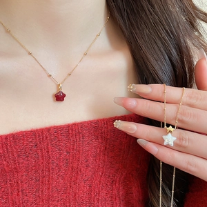 Detailed view of two gold-plated star pendant necklaces with red and white zircon accents