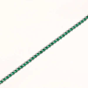 Macro view of silver tennis bracelet with single row of round emerald green zircons