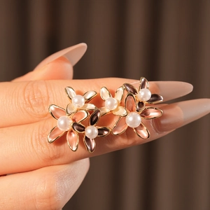 Detailed view of enamel flower earrings with pearl centers and gold-plated edges