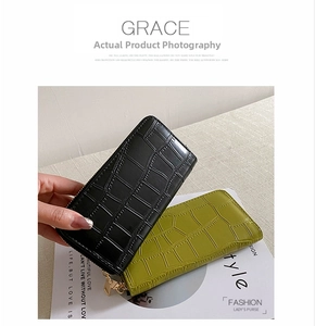 Close-up of crocodile pattern leather wallets in black and green with gold zippers