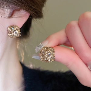 Close-up of gold-plated square stud earrings with champagne diamonds and silver needle