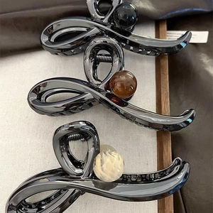 Macro detail of three elegant metal hair claws with glossy finish and large pearls