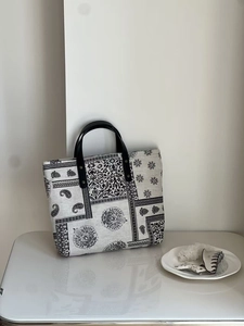 Close-up of black and white paisley cotton linen tote with black leather rivet handles