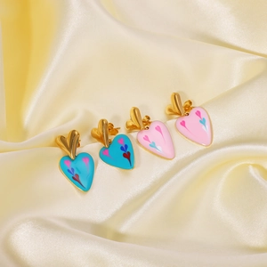 Boucles d'oreilles cœur en émail rose et bleu sur un élégant tissu en soie jaune