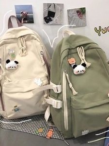 Detail view of cream and green canvas backpacks with buckle straps and front zipper pockets