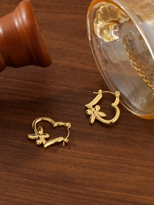 Makroaufnahme goldener Herzohrringe mit Blumenakzenten auf einer Vintage-Holzoberfläche