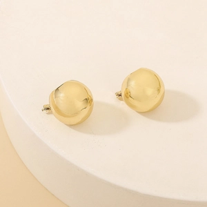 Minimalist golden spherical earrings with a smooth polished mirror finish on a stone display