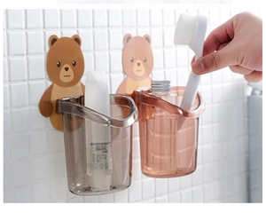 Detail view of wall-mounted bear toothbrush holder being used on white tile wall