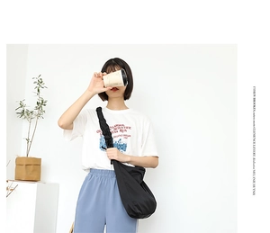 Detail of black nylon crossbody bag featuring stylish pleated shoulder strap design
