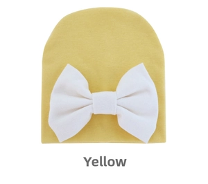 Detail of yellow knit baby hat featuring a large soft white bow on a white background