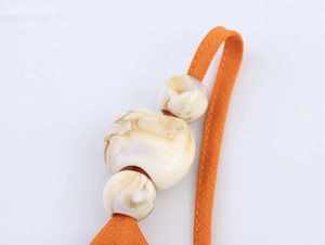 Détail macro de la sangle en tissu orange avec perles en résine marbrée décoratives