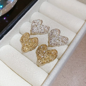 Detail view of heart-shaped hollow metal earrings with sparkling zircon inlay in a velvet box