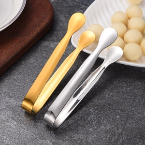 Polished gold and silver stainless steel sugar tongs on gray marble tabletop
