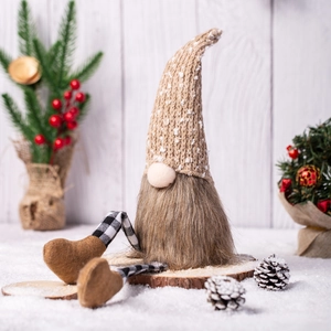 Nordic Christmas gnome plush with plaid legs and knit hat on rustic wooden background
