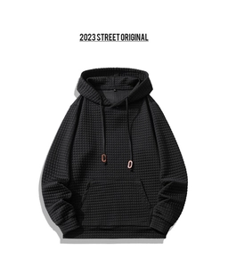 Detail of black waffle texture hoodie featuring kangaroo pocket and adjustable drawstring