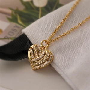 Close-up of a heart-shaped gold pendant necklace with cubic zirconia on a soft pouch