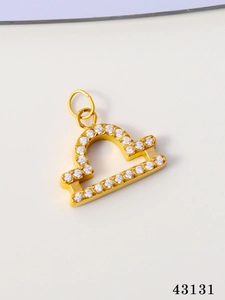 Detailed close-up of golden Libra zodiac charm with micro-pave cubic zirconia crystals