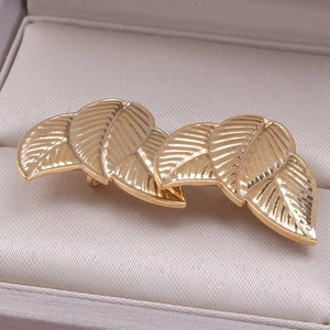 Macro detail of golden leaf earrings with vein texture on champagne satin lining