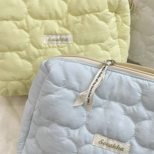 Close-up of quilted cloud pattern makeup bags in light yellow and blue with metal zippers